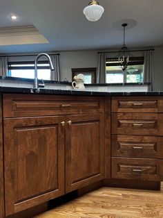 an empty kitchen with wooden cabinets and black counter tops in the middle of the room