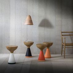 three wooden stools sitting next to each other in front of a white wall and chair