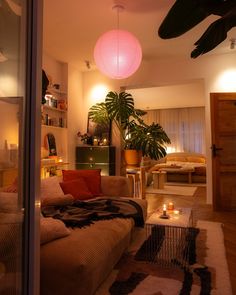 a living room filled with furniture and a pink light hanging over the top of it