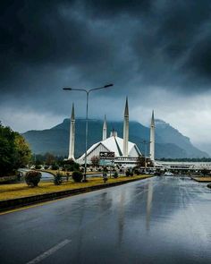 a rainy day in the middle of a city with tall buildings on both sides and dark clouds overhead