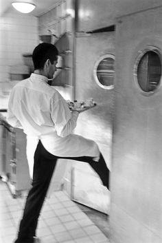 a man is jumping in the air to catch something out of an open refrigerator door