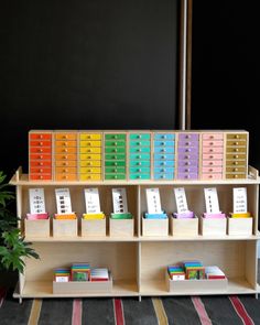 a book shelf filled with lots of books and binders next to a potted plant