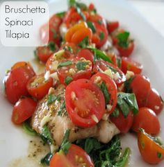 a white plate topped with chicken, tomatoes and spinach