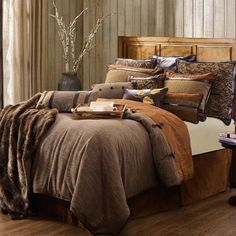 a bed with brown and tan comforters in a bedroom next to a wooden headboard