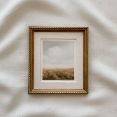 a painting hanging on the side of a wall next to a white cloth covered bed