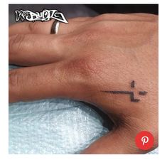 a person's hand with a cross tattoo on the left side of their finger