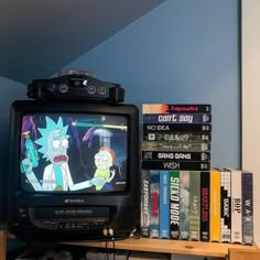 a television sitting on top of a wooden shelf next to a pile of books and dvds