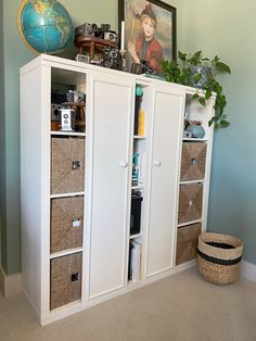 a white bookcase with baskets and pictures on top