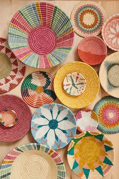 many colorful baskets are arranged on a wooden surface with different patterns and colors in the middle