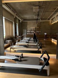 an empty gym with rows of treadmills and people walking in the distance behind them