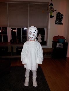 a person in a white costume standing on a black rug and looking at the camera