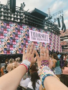 many people are holding their hands up in front of a large crowd at a concert