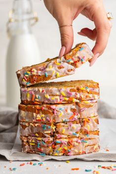 a person reaching for a piece of cake with sprinkles