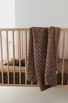 a baby crib with two brown blankets hanging from it's sides and another blanket on top of the crib