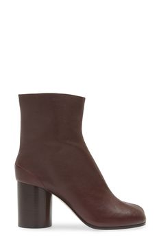 Inspired by the Japanese tabi sock, this iconic split-toe boot is made from supple leather and set on a cylindrical heel that keeps the palette monochromatic. 3" (76mm) heel (size 38.5) 6" shaft Hook closure Leather upper, lining and sole Made in Italy Women's Designer Shoes Burgundy Calf Leather Boots For Fall, Modern Calf Leather Heeled Boots With Contrasting Heel, Modern Heeled Boots With Contrasting Heel, Modern Heeled Boots With Rubber Heel Cap For Fall, Split Toe Boots, Tabi Boots, Tabi Socks, Maison Margiela Tabi, Margiela Tabi