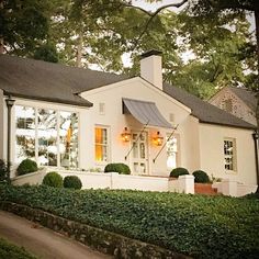 a white house with trees and bushes around it's front door, in the evening