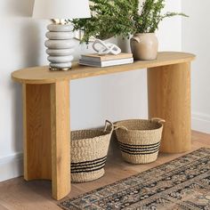 a wooden table with two baskets on top of it next to a lamp and rug