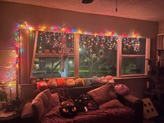 a living room filled with lots of furniture and christmas lights on the windowsills