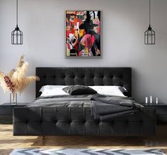 a bedroom with grey walls and black bedding, artwork on the wall above it