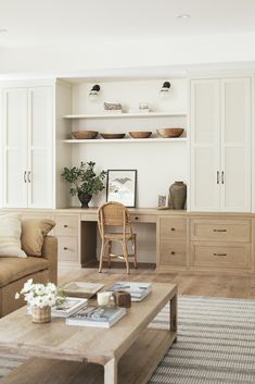 a living room filled with furniture and lots of white cupboards on top of a wooden table