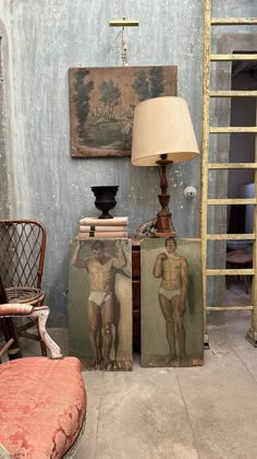 an old room with two paintings on the wall and a lamp in front of it