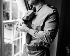 a man adjusting his tie in front of a window