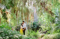 a man and woman standing in the middle of a forest with lots of green plants