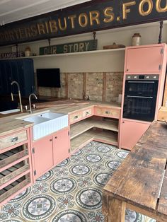 an old fashioned kitchen with pink cabinets and floor tiles on the floor, along with a large wooden table