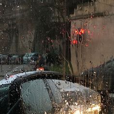 rain is falling on the windshield of a car as it sits in front of a building