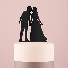 a wedding cake topper with a silhouette of a bride and groom kissing on it