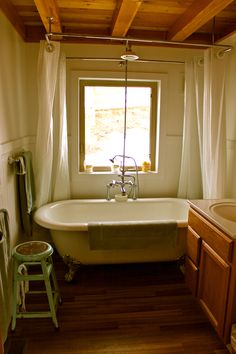 an old fashioned bathtub sits in the corner of a bathroom with wood flooring