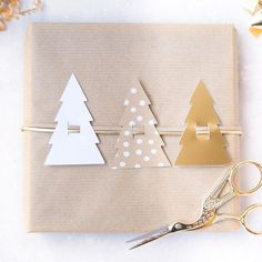 a pair of scissors sitting on top of a piece of paper next to some christmas trees