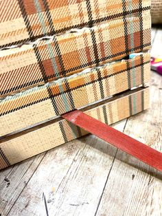 a pair of scissors sitting on top of a wooden table next to some plaid material