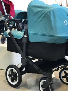 a blue stroller with two baby carriages in the background