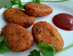 four fried food items on a plate with ketchup and parsley garnish