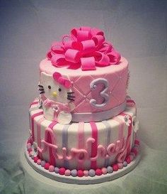 a hello kitty birthday cake is decorated with pink and white stripes, bows, and the number 3