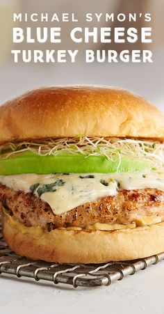 a burger with cheese, lettuce and sauce on it sitting on a cooling rack