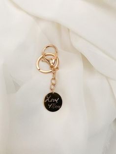 a gold keychain that says sorry mom on it with a black circle charm