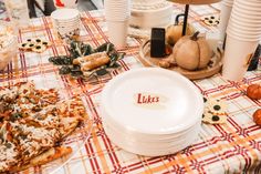 a table topped with plates and pizza covered in toppings on top of a checkered table cloth