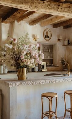 a kitchen with two stools next to a counter and some flowers in a vase