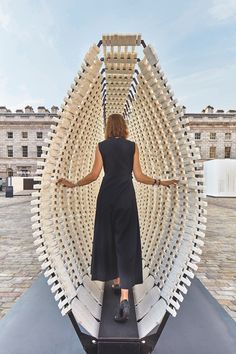 a woman is standing in front of a sculpture