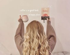 a woman sitting on her bed reading a book and holding a coffee mug in front of her head