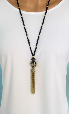 Bohemian Style black and gold beaded necklaces, handmade by Ralston Originals. These beautiful tassel necklaces come in your choice of 3 different Styles. I made the tassels with gold metal chain, and a large antique gold cap. I made the first necklace (pictures 1-3), with a large black bead with gold metal dots, and a black bead with gold stripes. The beaded chain is made with black seed beads, and gold acrylic beads. This necklace is 28 inches long, and has a lobster clasp. I made the second n Bohemian Long Necklace With Black Round Beads, Gold Beaded Tassel Long Necklace, Gold Beaded Tassel Necklace, Bohemian Gold Beaded Necklaces With Tassels, Black Tassel Necklace With Adjustable Fit, Black Bohemian Jewelry With Tassels, Adjustable Black Tassel Necklace, Gold Tassel Necklace For Festivals, Bohemian Black Beaded Necklaces With Fringe