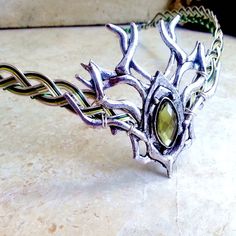 "A woodland stag branch design with a mossy green gem centerpiece is the focal point of this unisex Celtic elven circlet, inspired by the forests of Ireland and Scotland. The Celtic weave base is silver with green accent wires woven in. Three choices of green are available... light green, shown, medium (grass) green, and dark green. Green wire colors will be adjusted accordingly. The circlet can be worn by either men or women and depending on the activity level, can be worn as is, or held in pla Circlet Crown, Elven Circlet, Elven Fairy, Elven Wedding, Ireland And Scotland, Crown Headdress, Celtic Green, Male Crown, Celtic Weave