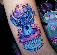 a blue cupcake tattoo with an elephant on it's arm, and another cartoon character in the background