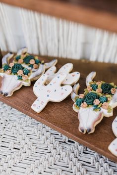 decorated cookies are arranged in the shape of deer heads on a wooden board with flowers