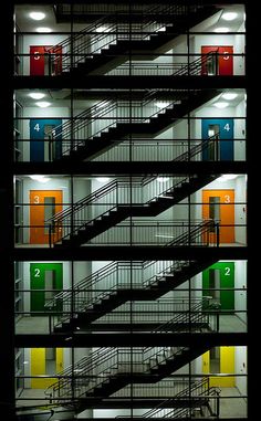 the staircases are lit up at night in an empty building with doors and windows