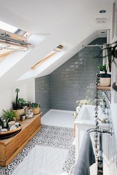 an attic bathroom with tiled floor and skylights above the bathtub is decorated in black and white tiles