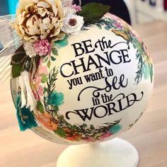 a decorative ball with flowers on it and the words be the change you want to see in the world