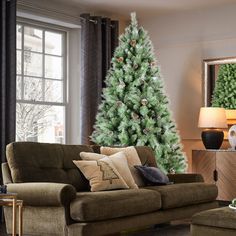 a living room filled with furniture and a christmas tree in the corner near a window